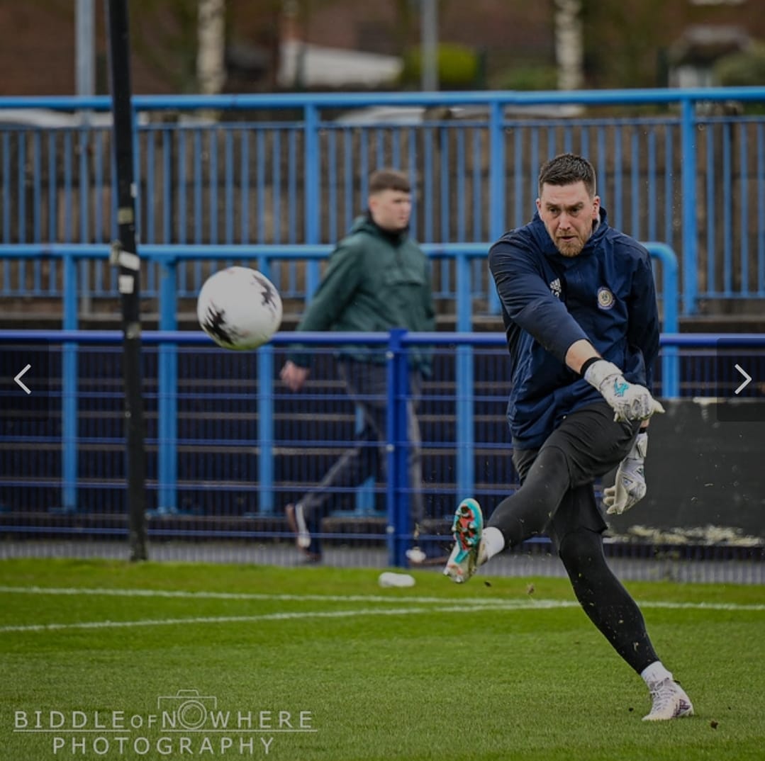 Goalkeeper striking a football on matchday